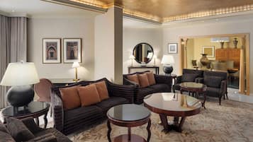 A spacious living room with a dark patterned sofa, two round tables, and a large mirror.
