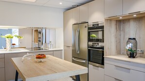 Una cucina moderna con tavolo in legno, elettrodomestici in acciaio inossidabile e una piccola pianta in vaso.