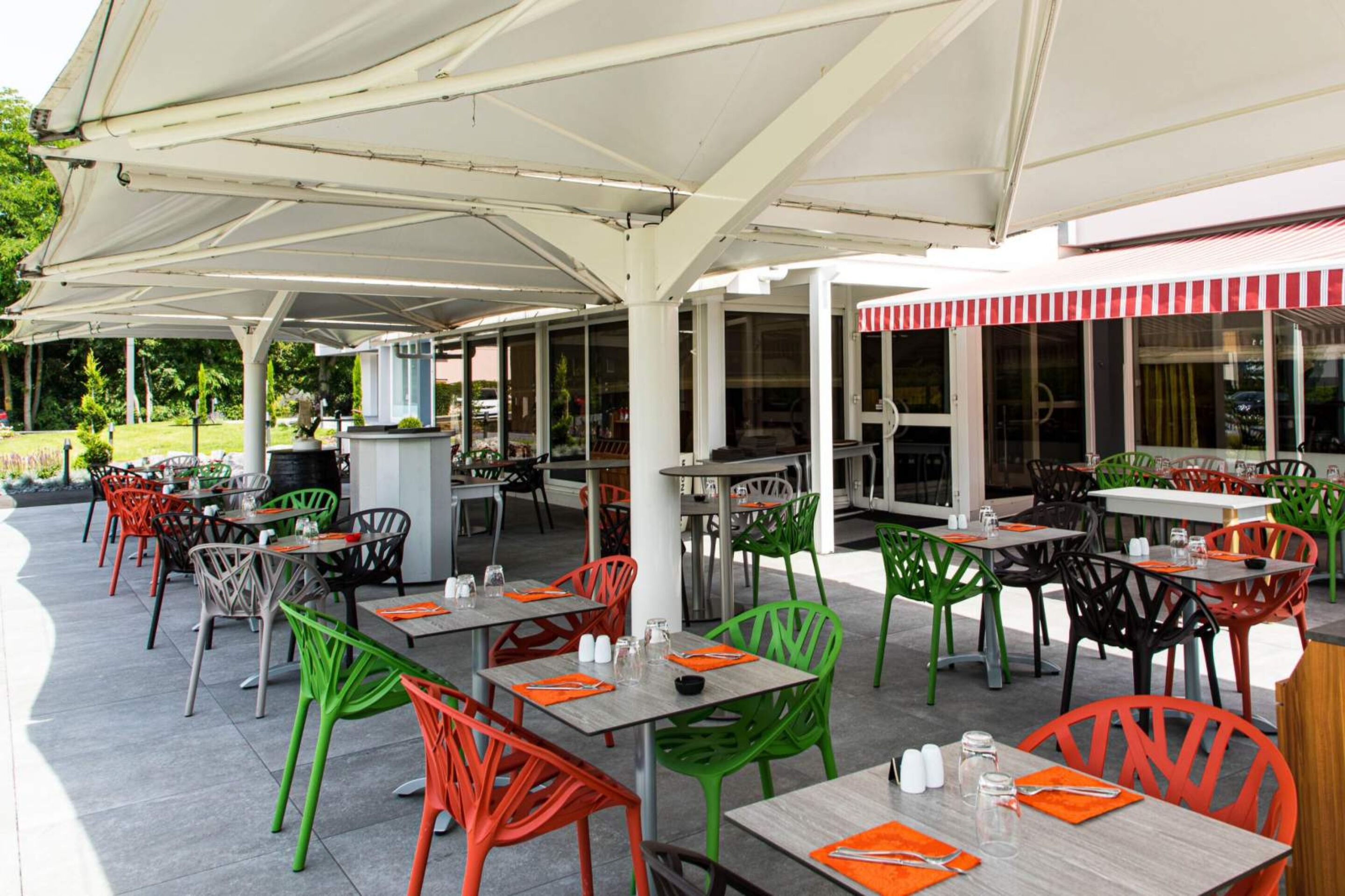 An outdoor patio area with tables and chairs, covered by a white canopy.