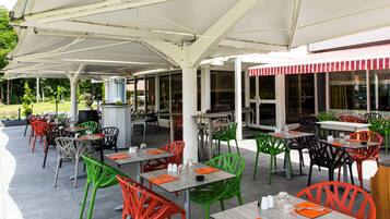 An outdoor patio area with tables and chairs, covered by a white canopy.
