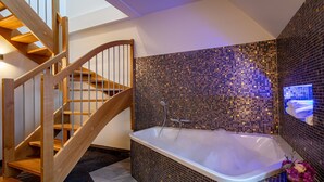 Un bagno moderno con una scala in legno, una vasca da bagno ampia e pareti rivestite di mosaici.