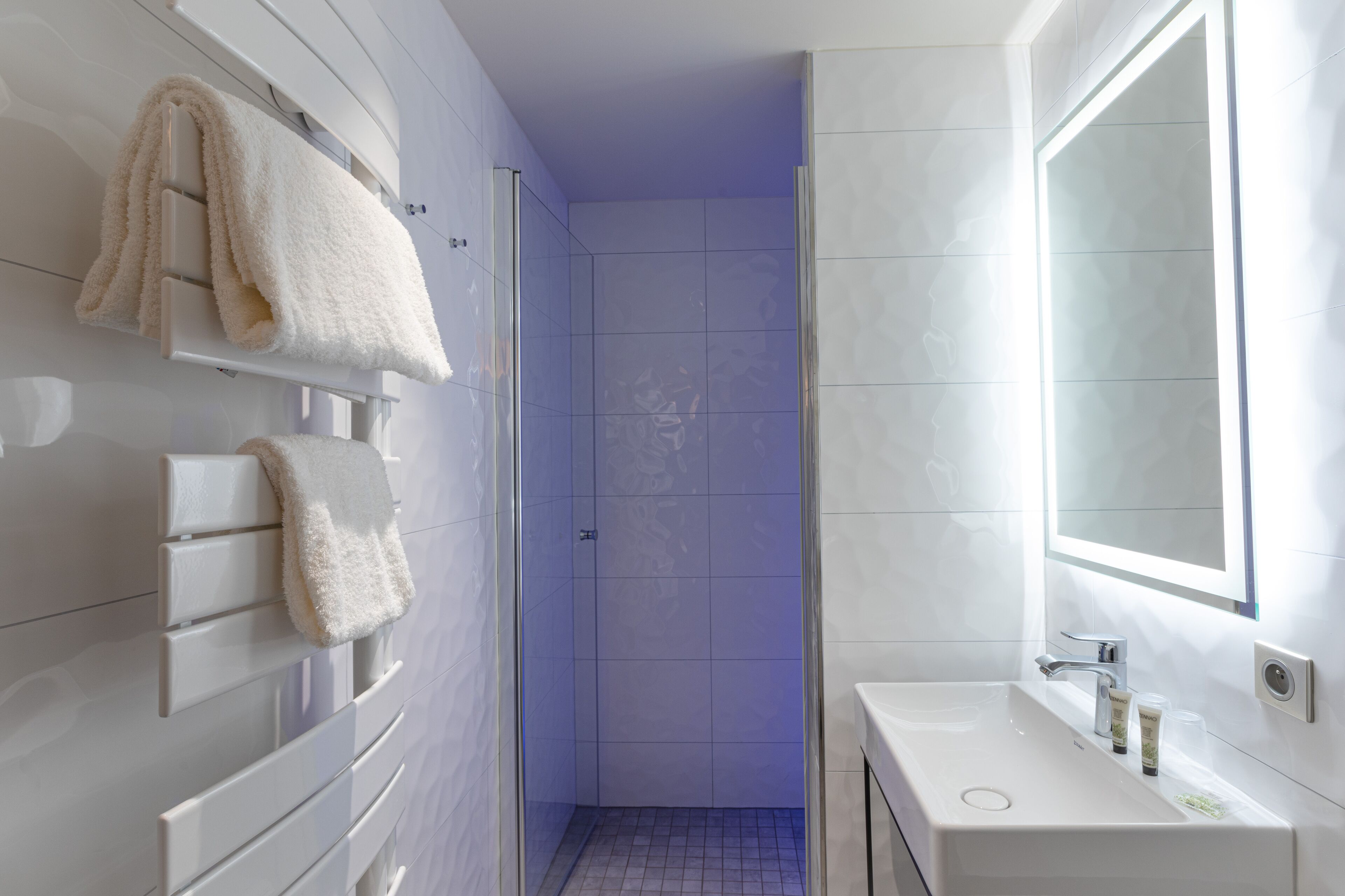 A modern bathroom with a white sink, mirror, and towel rack.