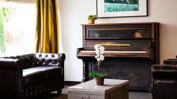 Een woonkamer met een piano, een bank en een kleine tafel met een plant.