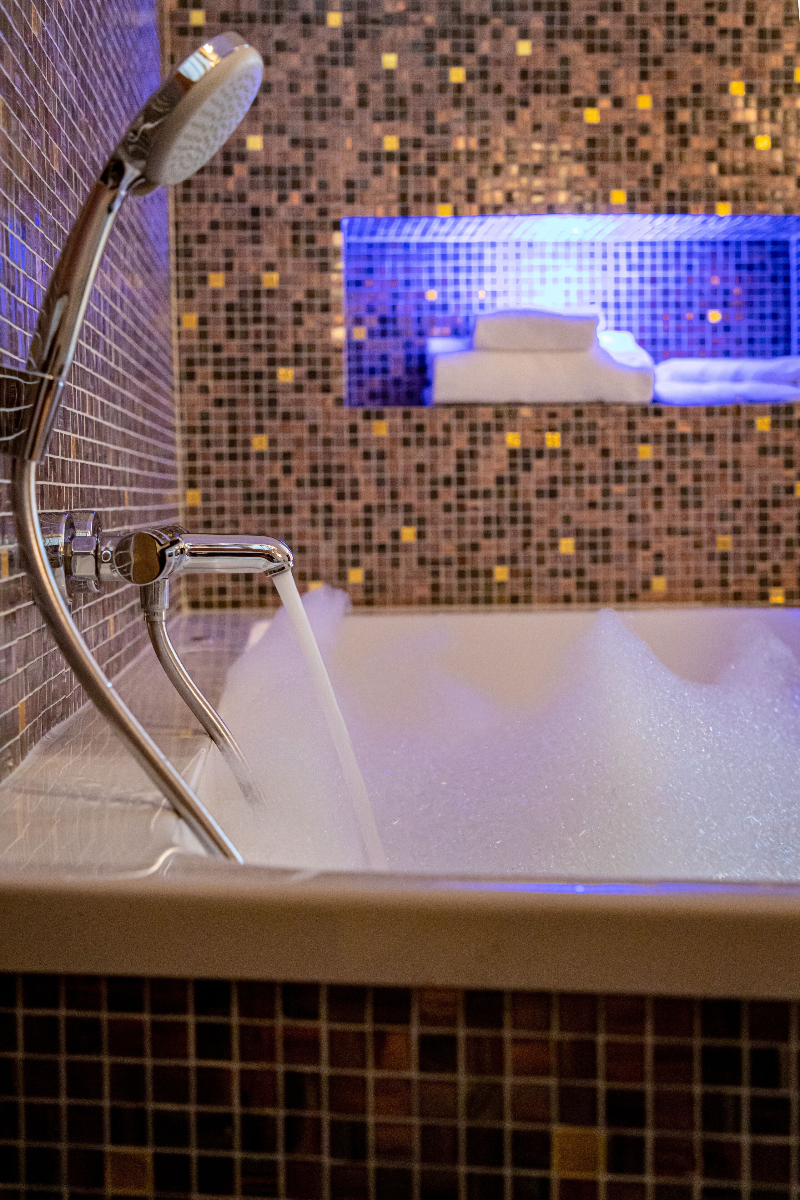 A bathroom with a shower, a sink, and a tiled wall.