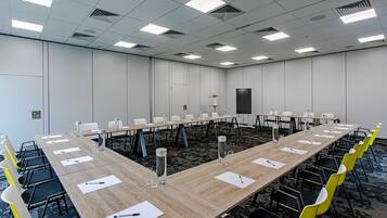 A conference room with a long table, chairs, and a carpeted floor.