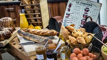 Een houten tafel met diverse gebakken producten, waaronder brood en gebak, en potten jam.