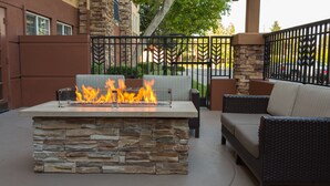 An outdoor patio with a stone fire feature and wicker furniture.