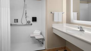 A modern bathroom with a walk-in shower, a white sink, and a large mirror.
