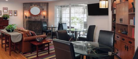 A modern living room with a glass dining table, leather sofas, and a fireplace.