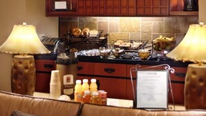 A breakfast buffet with various food items and beverages, a menu sign, and a decorative lamp.