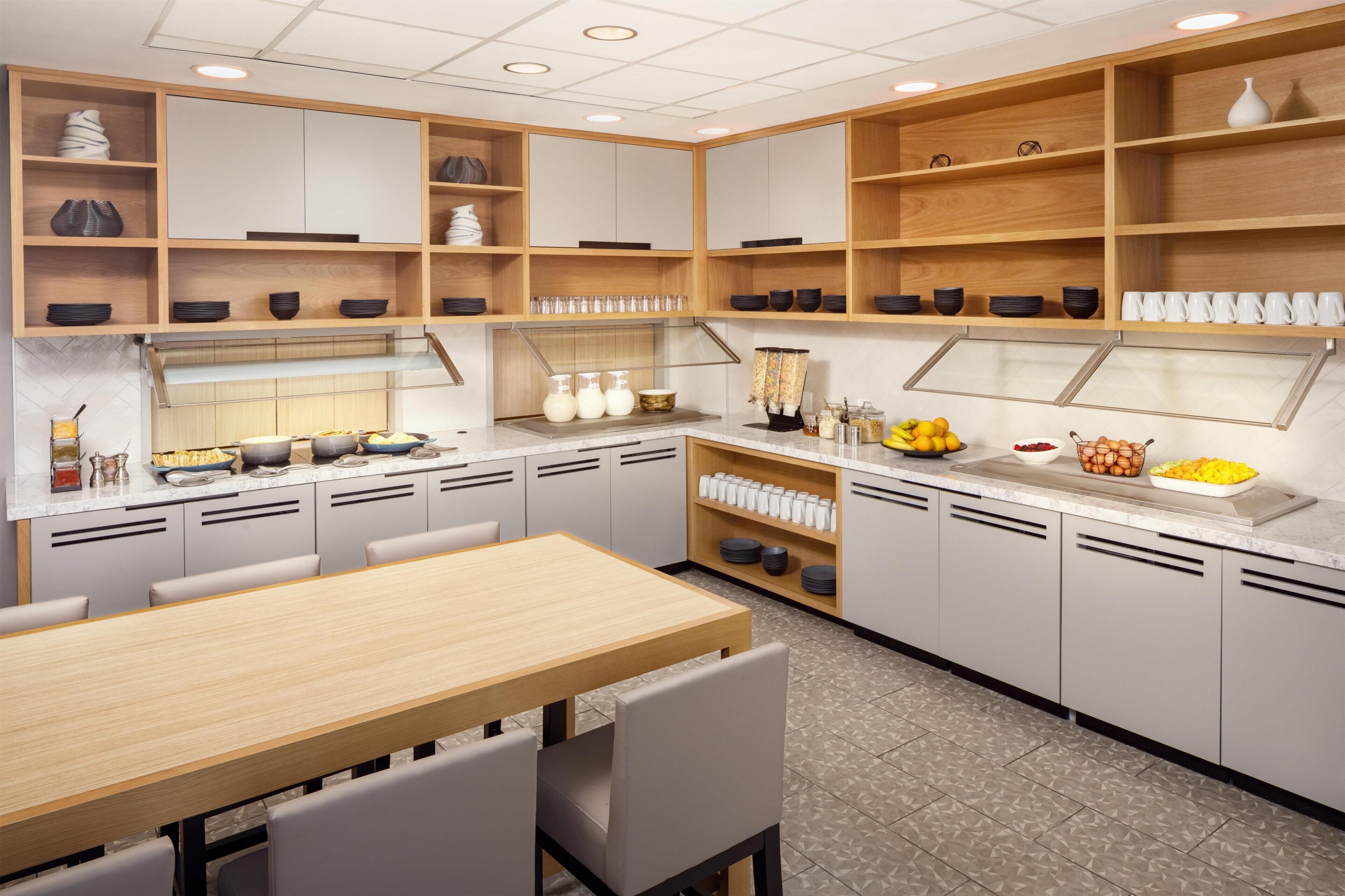 A modern kitchen with built-in cabinets, a central island, and a dining area with chairs.