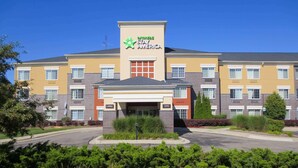 A multi-story hotel with a yellow facade, a green logo, and a 'Lobby' sign. - Auburn Hills Extended Stay Inn (Auburn Hills)