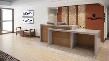 Un moderno mostrador de recepción con un panel de madera y el logotipo de Candlewood Suites. En la pared hay dos obras de arte abstracto enmarcadas y una alfombra estampada en el suelo.
