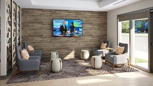 A modern lobby with a large TV displaying a news broadcast, comfortable seating, and a view of the outdoors. - Candlewood Suites Beachwood Cleveland by IHG (Beachwood)