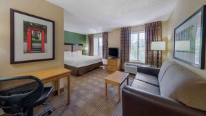Ein Hotelzimmer mit Bett, Schreibtisch, Stuhl, Fernseher und einer Couch.