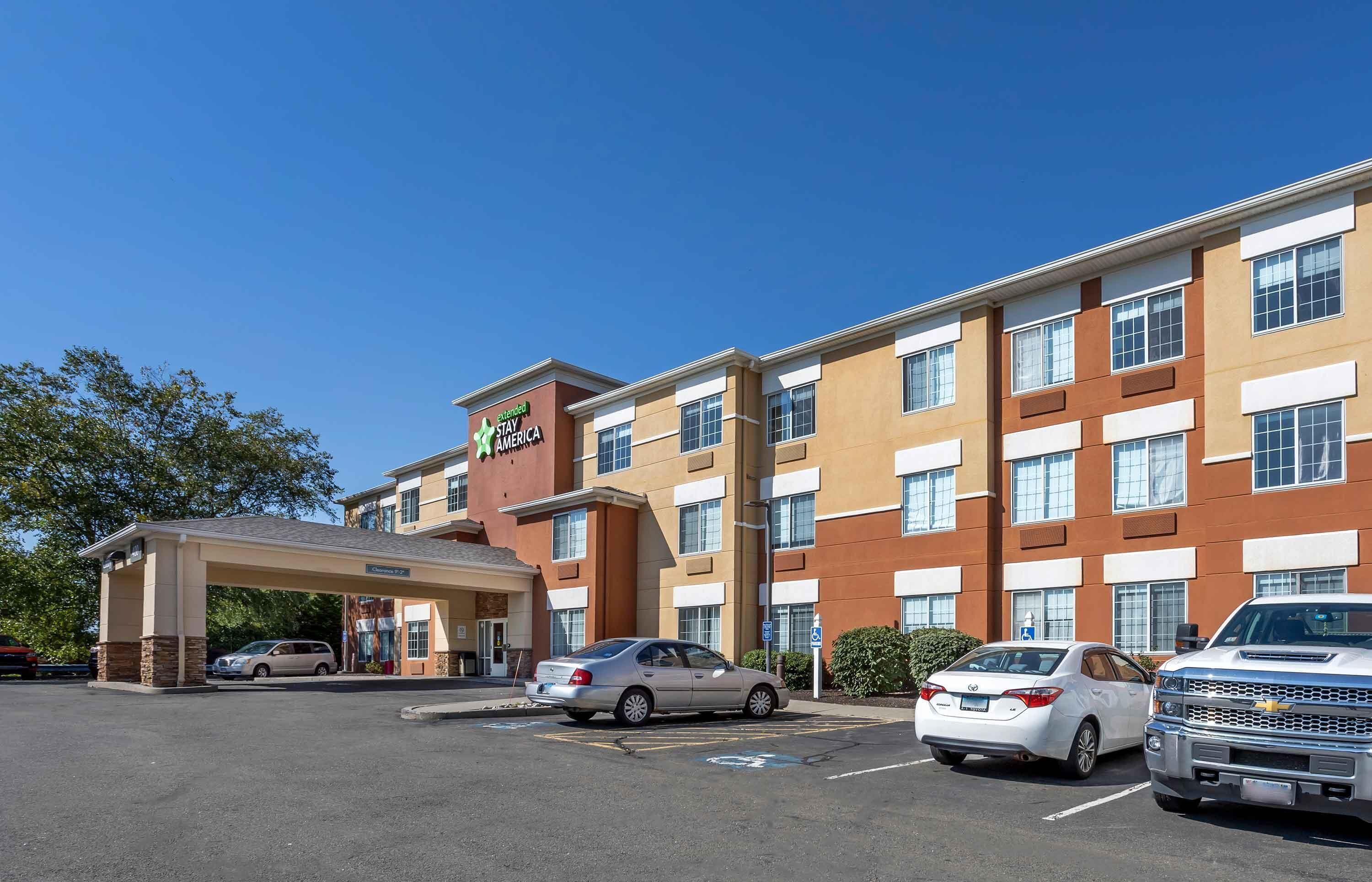 A Staybridge Inn hotel with a covered entrance, multiple parking spaces, and a clear blue sky.