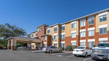 A Staybridge Inn hotel with a covered entrance, multiple parking spaces, and a clear blue sky.
