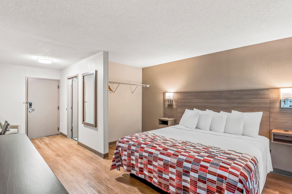 A hotel room with a large bed, a desk, and a mirror.