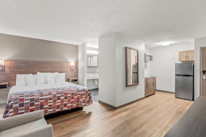 Una habitación de hotel moderna con una cama grande, una kitchenette y un baño.