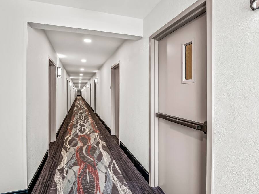 A long, narrow hallway with a patterned carpet and white walls.