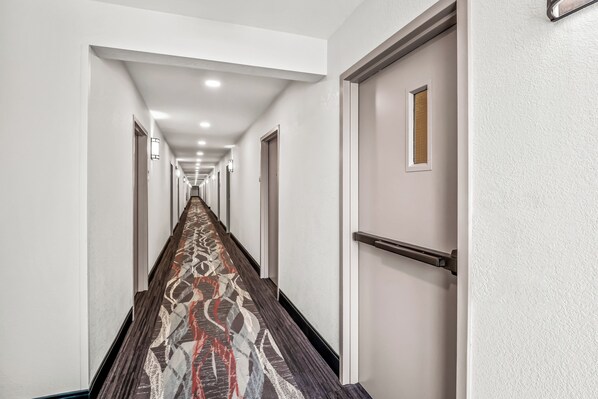 A long, narrow hallway with a patterned carpet and white walls.