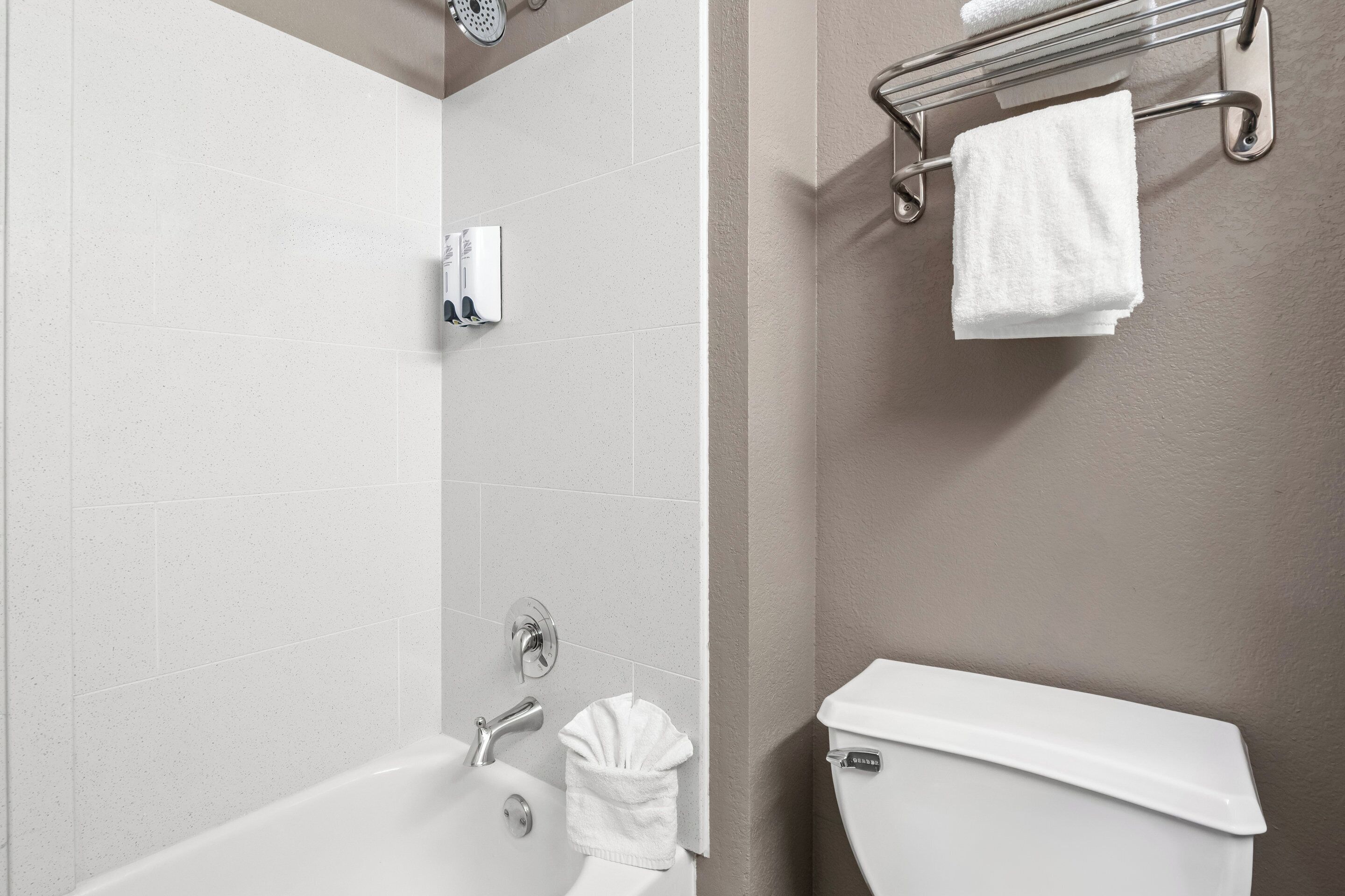 A bathroom with a bathtub, a toilet, and a towel rack.