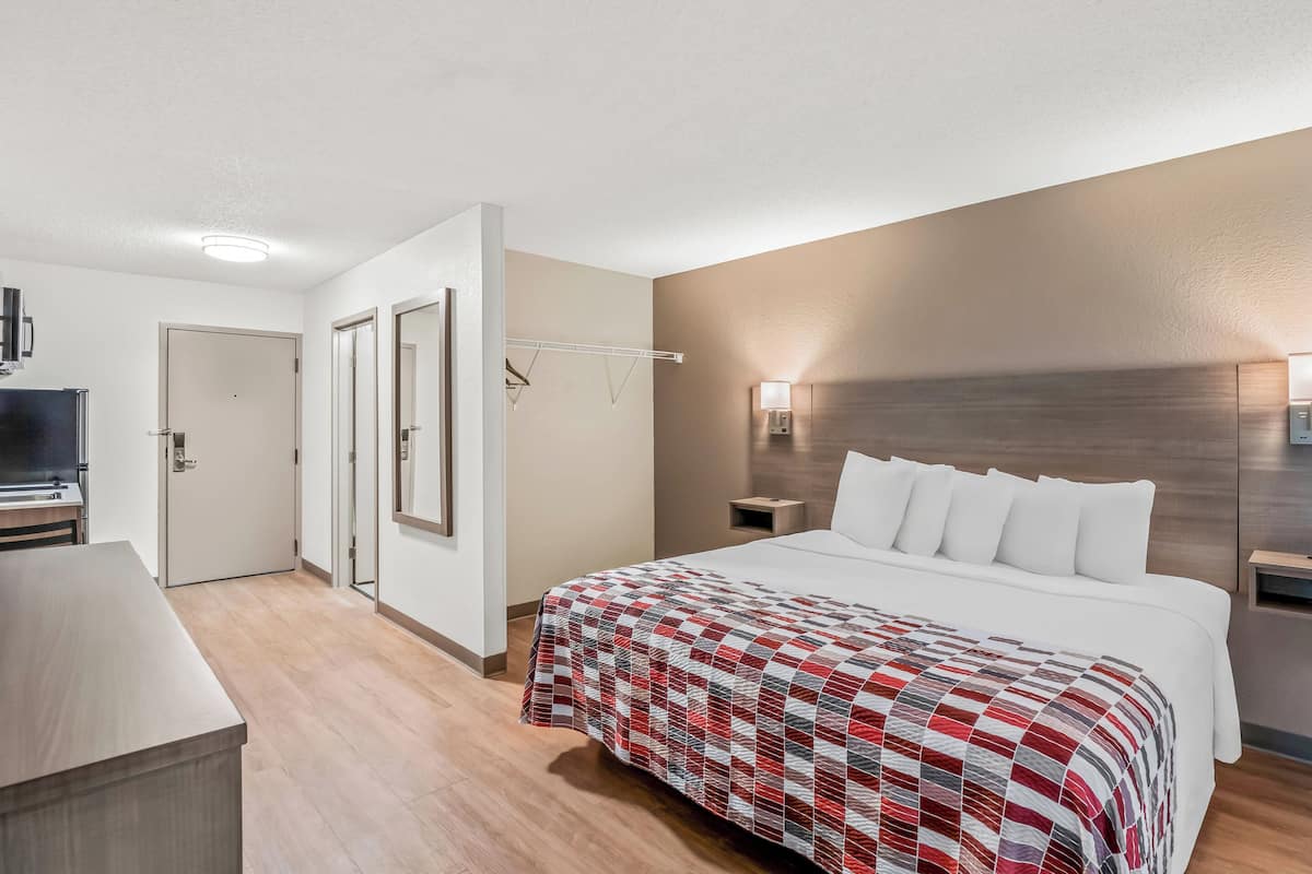 Ett hotellrum med en säng, ett skrivbord, en tv och en garderob.