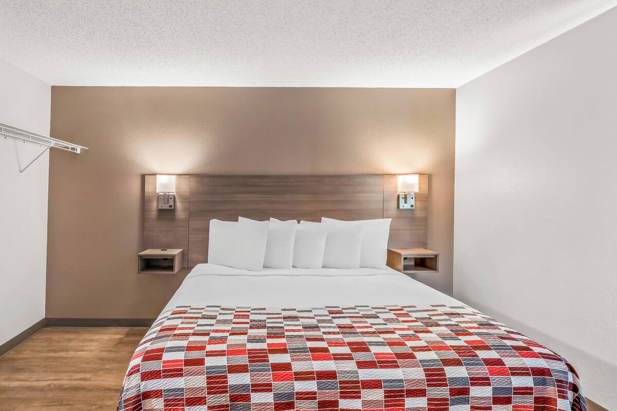 Ett hotellrum med en stor säng, två sängbord och en sänggavel med inbyggd belysning.