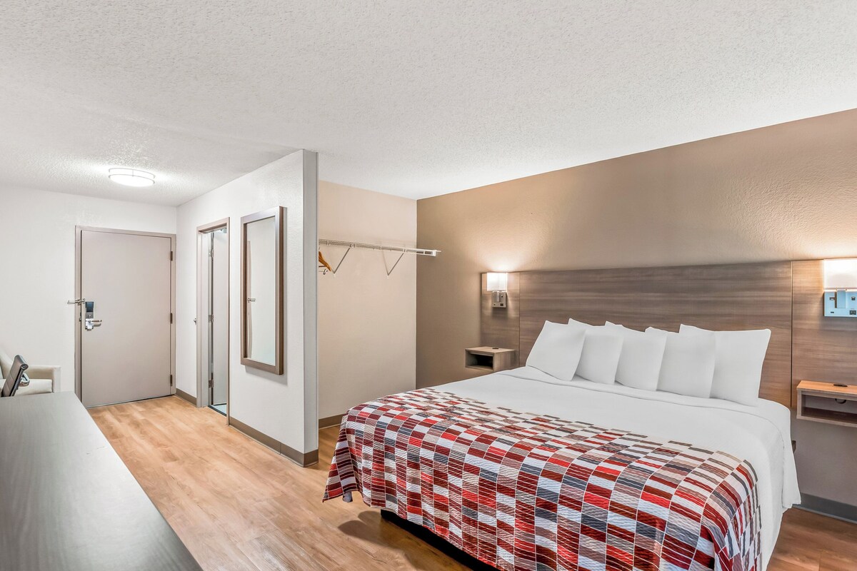 A hotel room with a large bed, a desk, and a mirror.