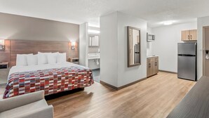 Une chambre d’hôtel moderne dotée d’un grand lit, d’une kitchenette et d’une salle de bain.