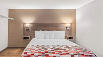 A hotel room with a large bed, two bedside tables, and a headboard with integrated lighting.