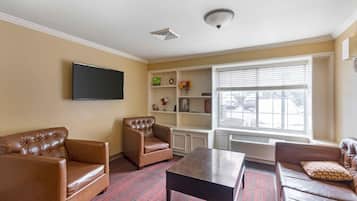 A living room with a flat-screen TV, leather sofas, a coffee table, and a window with blinds.