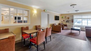 A hotel room with a dining area, a sofa, a TV, and a window with blinds. - Extended Stay America Suites St Louis Westport Central (Maryland Heights)
