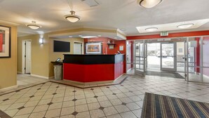 A reception area with a red counter, a welcome sign, and an exit door. - Extended Stay America Suites St Louis Westport Central (Maryland Heights)