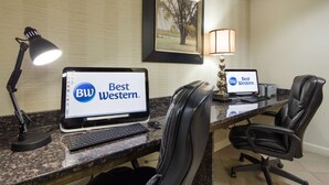 Dos escritorios con computadoras mostrando la marca 'Best Western', una foto enmarcada en la pared y una lámpara sobre el escritorio.