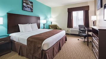 A hotel room with a large bed, two bedside tables, a desk, a chair, and a window with curtains.