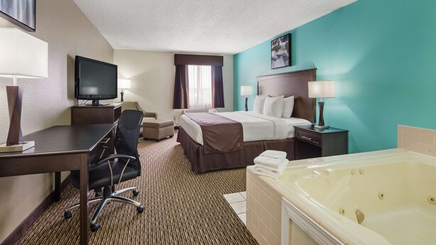 Habitación de hotel con cama, escritorio, silla, televisor y bañera.