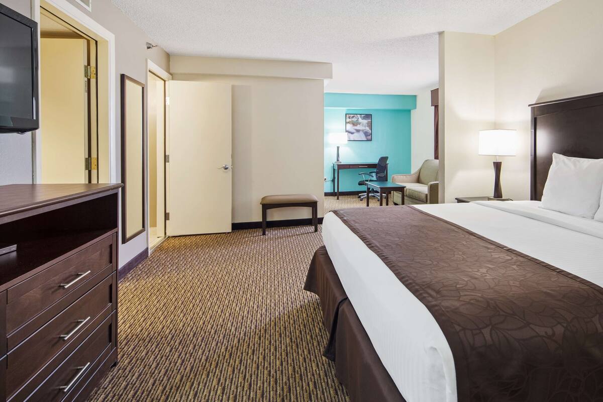 Une chambre d’hôtel avec un grand lit, un bureau, une chaise, une télévision et une commode.
