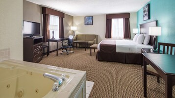 Habitación de hotel con cama, escritorio, silla, televisor, lámpara de escritorio, lámpara de pie y bañera.