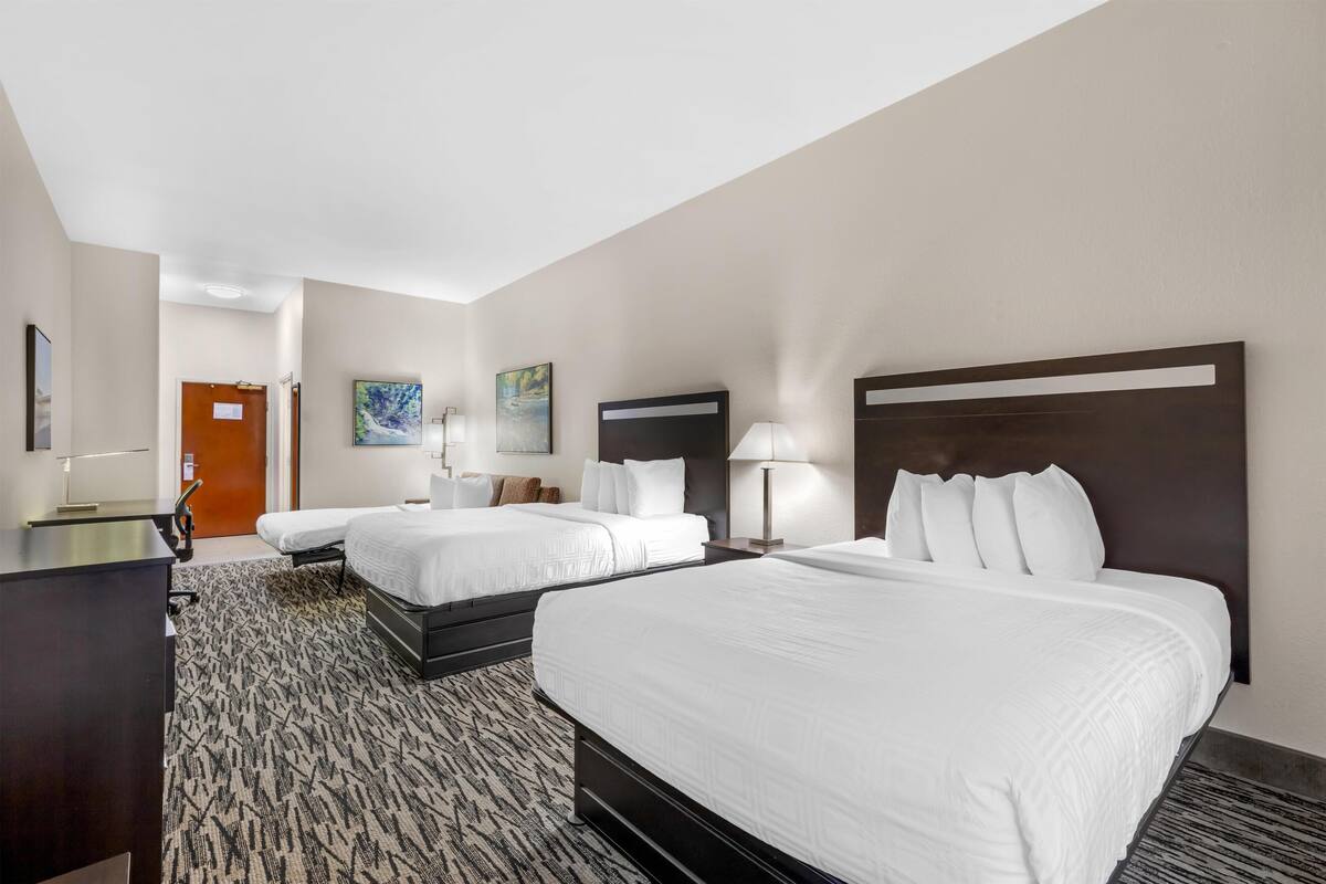 A hotel room with two beds, a desk, and a carpeted floor.