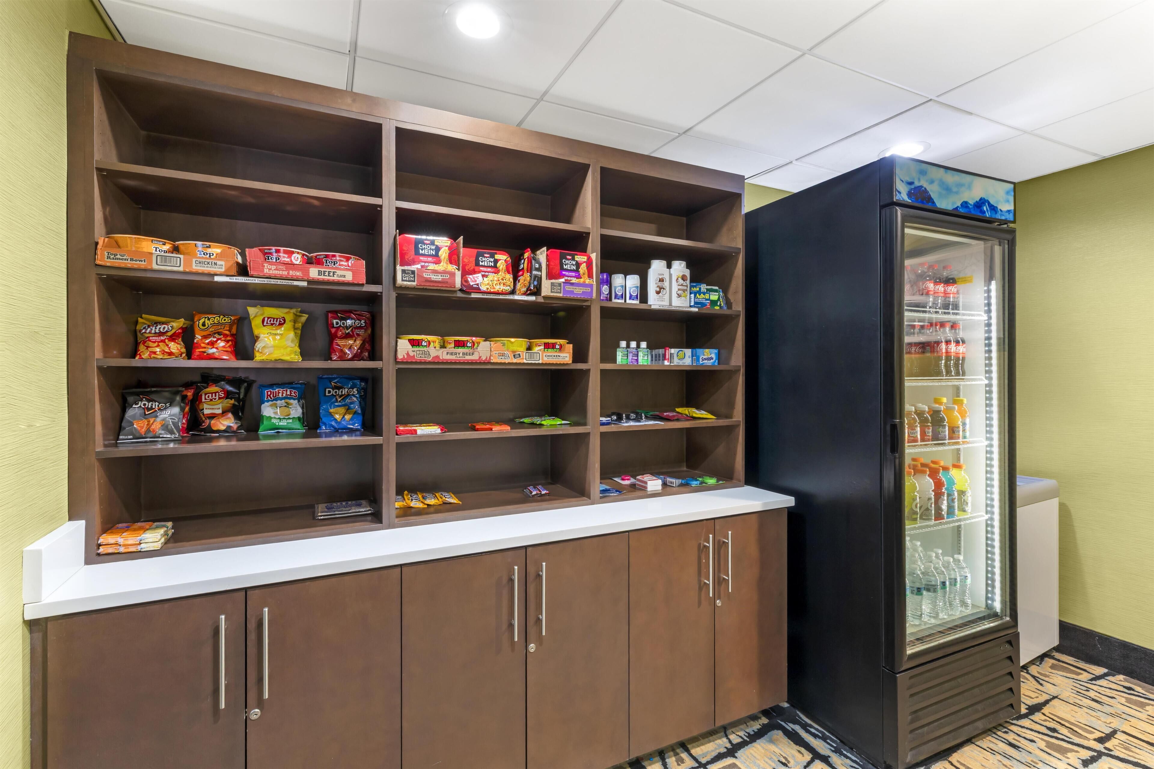 A snack bar with shelves stocked with various snacks and beverages, and a refrigerator with drinks.
