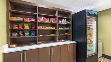 A snack bar with shelves stocked with various snacks and beverages, and a refrigerator with drinks.