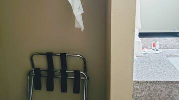 A hotel room with a bed, a metal rack with hangers, and a small table with toiletries.