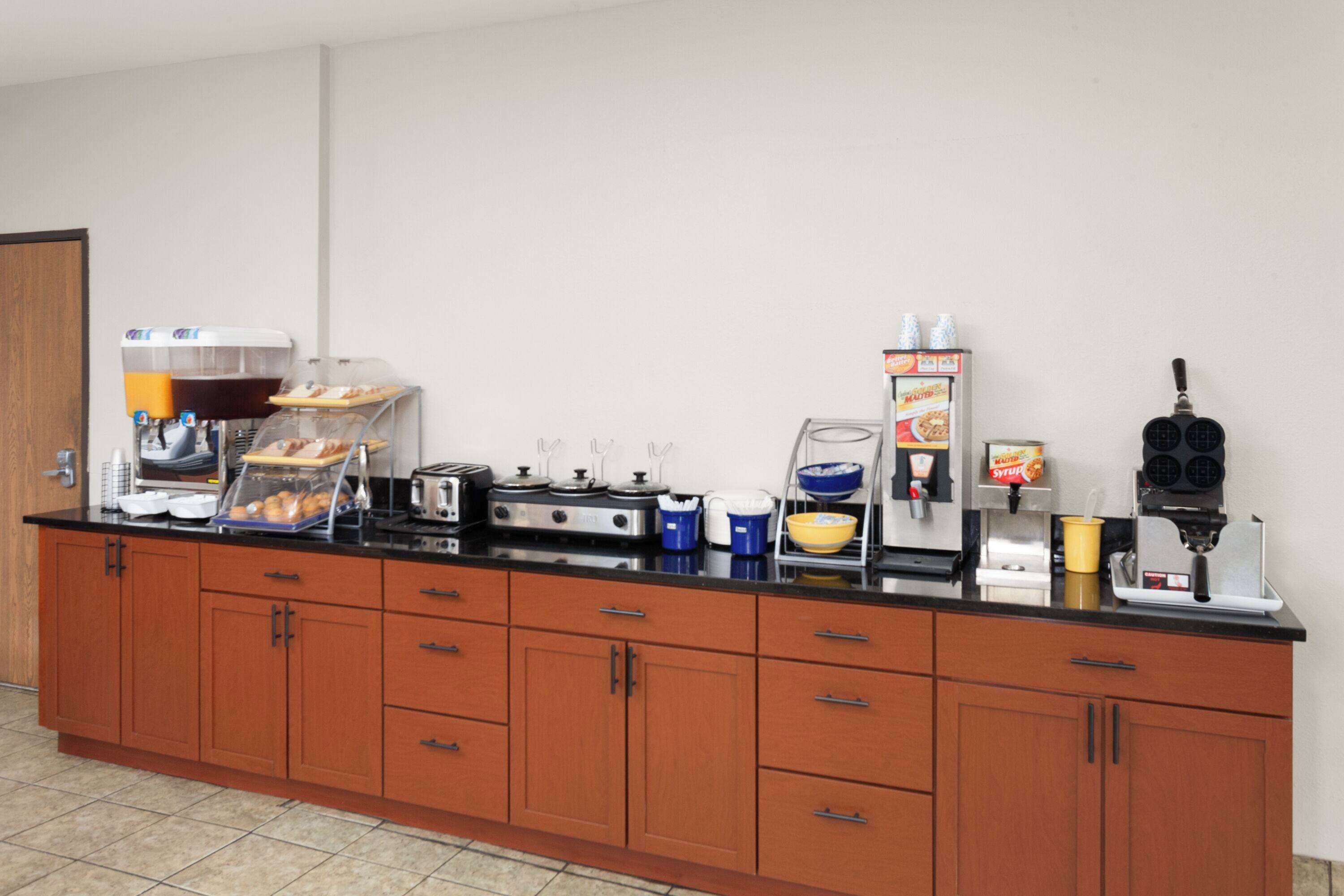 Una kitchenette con cafetera, tostadora, hervidor y varios recipientes para alimentos.