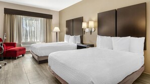 A hotel room with two beds, a red chair, a lamp, and a window with curtains. - Best Western Plus Heritage Inn (Houston)