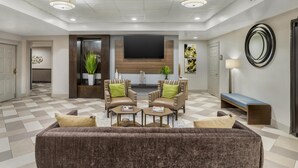 A modern living room with a sofa, two armchairs, a coffee table, a flat-screen TV, and a large mirror. - Best Western Plus Heritage Inn (Houston)