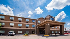 Un hotel Best Western con fachada marrón, múltiples ventanas y un acceso cubierto.