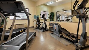 Un gimnasio con cintas de correr, elípticas y bicicletas estáticas.