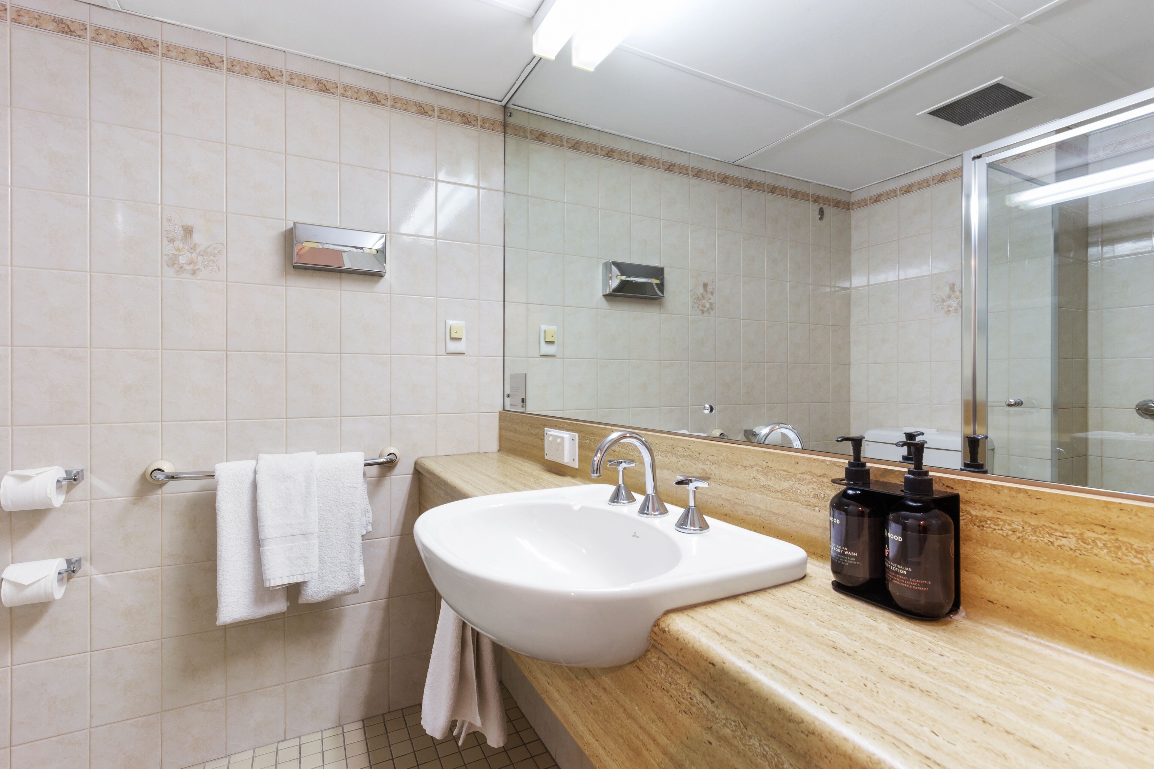 A bathroom with a sink, mirror, towel rack, and toiletries.