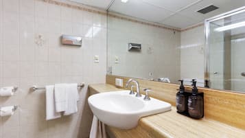 A bathroom with a sink, mirror, towel rack, and toiletries.